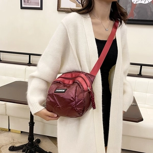 Quilted burgundy crossbody bag in padded nylon worn by model for casual fashion
