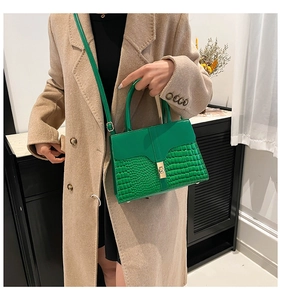 Detail view of emerald green leather bag featuring crocodile pattern on wool coat model