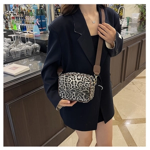 Detail of leopard print crossbody camera bag with wide brown strap on a model