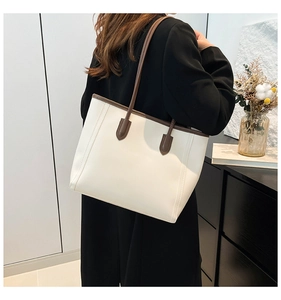 Detailed side view of cream white leather tote bag with brown contrast trim and slim straps