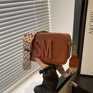 Brown leather camera bag with wide jacquard strap and embossed SM logo detail