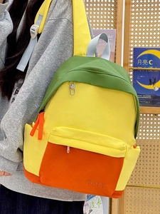 Detail of multi-color canvas backpack featuring yellow and green panels with TKSS logo