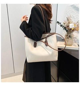 Detailed side view of a large cream leather tote bag with dark brown straps for daily commute