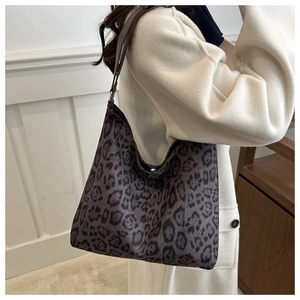 Detail of a stylish dark leopard print shoulder bag worn with an elegant cream coat