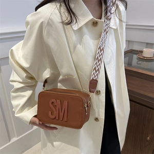 Retro brown camera bag with embossed letters and a wide geometric patterned shoulder strap
