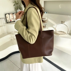 Brown leather tote bag featuring vertical stitching and minimalist shoulder straps