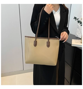 Close-up of beige leather tote bag with brown straps showing stitching details