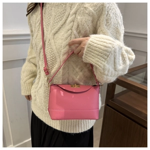 Détail du sac à main en cuir litchi rose avec fermoir doré porté par un mannequin