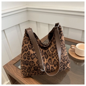 Detail of leopard print hobo bag with brown leather strap on a wooden coffee table