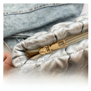 Dettaglio di borsa cosmetica trapuntata argento con cerniera dorata e pelle metallizzata