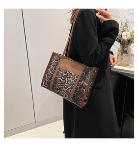 Détail d'un grand sac cabas à imprimé léopard porté à l'épaule dans un décor moderne