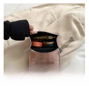 Macro view of pink metallic crossbody bag interior with silver star buckle and cosmetics