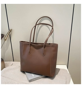 Detail view of the brown leather tote bag with elegant stitching and slim shoulder straps