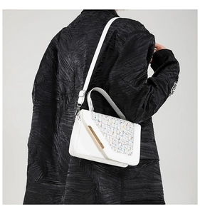 Détail du sac à main en cuir blanc avec rabat tissé et fermoir en métal doré