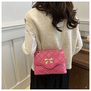 Detail of rose red quilted crossbody bag with golden bow buckle and chain strap