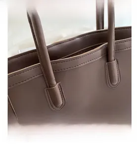 Detailed close-up of dark brown tote bag showing premium stitching and zipper closure