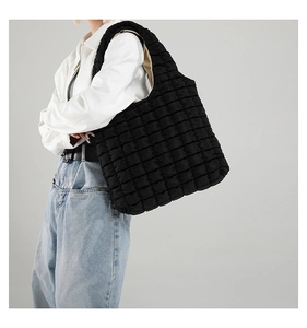 Detailed side view of black quilted puffy tote bag on model for casual styling