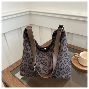 Detail shot of leopard print fabric bag with brown leather strap and metal buckle