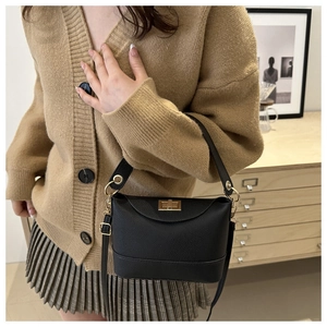 Détail du sac à main en cuir noir avec fermoir doré et poignée avec anneaux métalliques