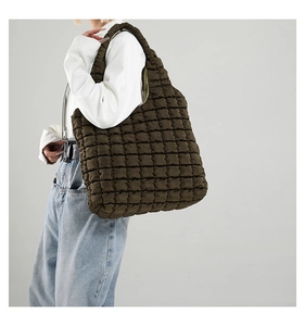 Detail view of olive green quilted bubble bag texture on female model's shoulder