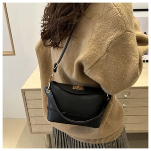 Détail du sac seau noir en cuir grainé avec fermoir doré rotatif et poignée de transport