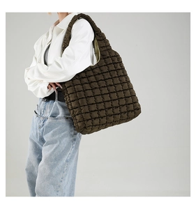Detailed macro view of the dark brown puffy quilted texture on a large cloud shoulder bag