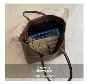 Spacious interior of dark brown tote bag holding tablet, wallet, and umbrella