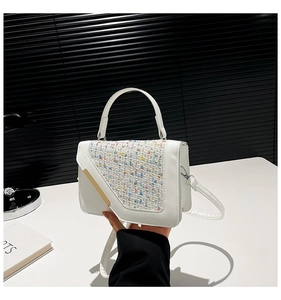 Détail rapproché du sac bandoulière blanc avec patchwork en tweed coloré et barre dorée