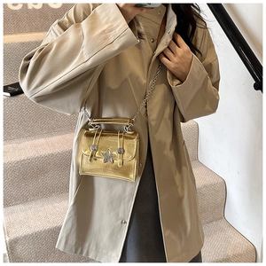 Detail of a chic golden metallic chain bag featuring a prominent star ornament