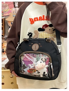 Detail of cute black bear crossbody bag with a transparent window and plush cow inside