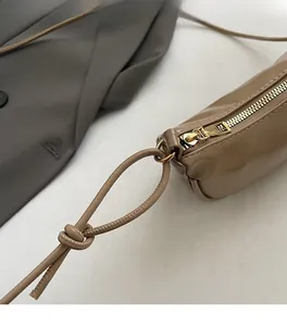 Close-up of smooth gold zipper and shiny khaki leather texture on a chic dumpling bag