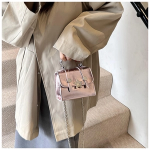 Detail of metallic pink crossbody bag with star-shaped buckle and silver chain strap