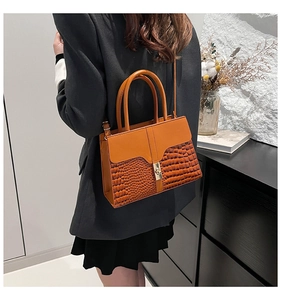 Detail of a brown crocodile pattern handbag with metal buckle and smooth leather finish