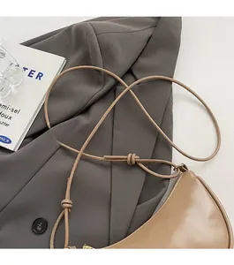 Detailed macro view of camel half-moon bag featuring a knotted thin shoulder strap