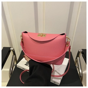 Détail d'un sac à bandoulière rose en cuir avec fermoir doré tournant et rabat chic