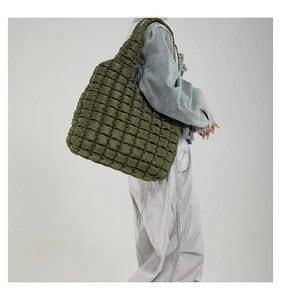 Close-up of olive green quilted cloud bag texture and wide shoulder strap on model