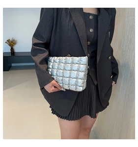 Dettaglio della borsa clutch trapuntata argento abbinata a un blazer grigio