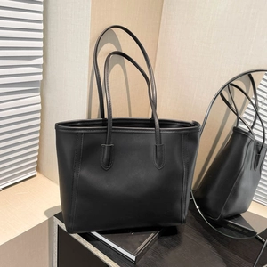Minimalist black tote bag with shoulder straps and visible stitching on mirror surface