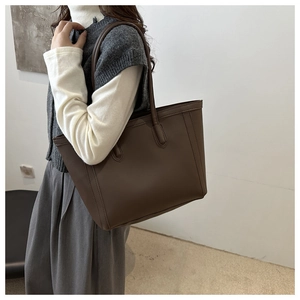 Detail view of the deep brown leather tote bag showing smooth matte texture and stitching