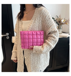 Dettaglio ravvicinato di una trousse trapuntata rosa tenuta da una modella in posa