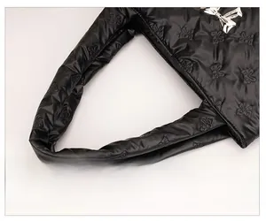 Detail van zwarte gewatteerde schoudertas met strikpatroon en zilveren strik-accessoire