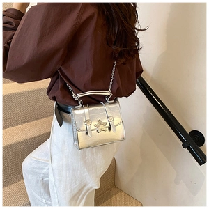 Detail of mini silver metallic crossbody bag featuring a star-shaped metal clasp and chain