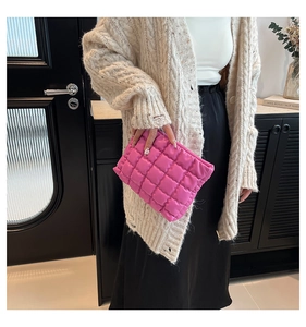 Dettaglio della borsa clutch trapuntata rosa acceso tenuta da una modella in interni chic
