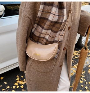 Close-up of beige moon-shaped leather crossbody bag with FASHION & BAGS gold lettering