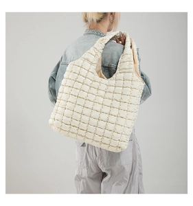 Close-up of creamy white quilted puff shoulder bag with soft textured fabric and wide strap