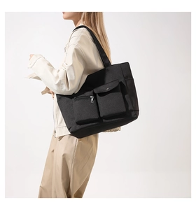 Close-up of large black nylon tote bag with functional pockets worn by a model