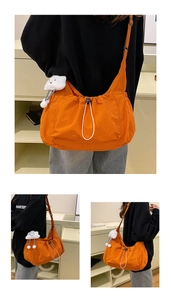 Detail of orange nylon tote bag showing drawstring closure and plush cloud charm