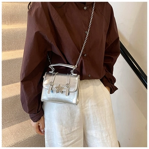 Detail of silver mirror crossbody bag with star buckle and metallic chain strap