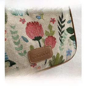 Detail of floral jacquard fabric texture and brown leather logo patch on canvas bag
