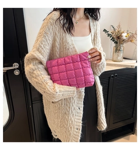 Dettaglio della pochette fucsia trapuntata con texture soffice e cuciture a diamante